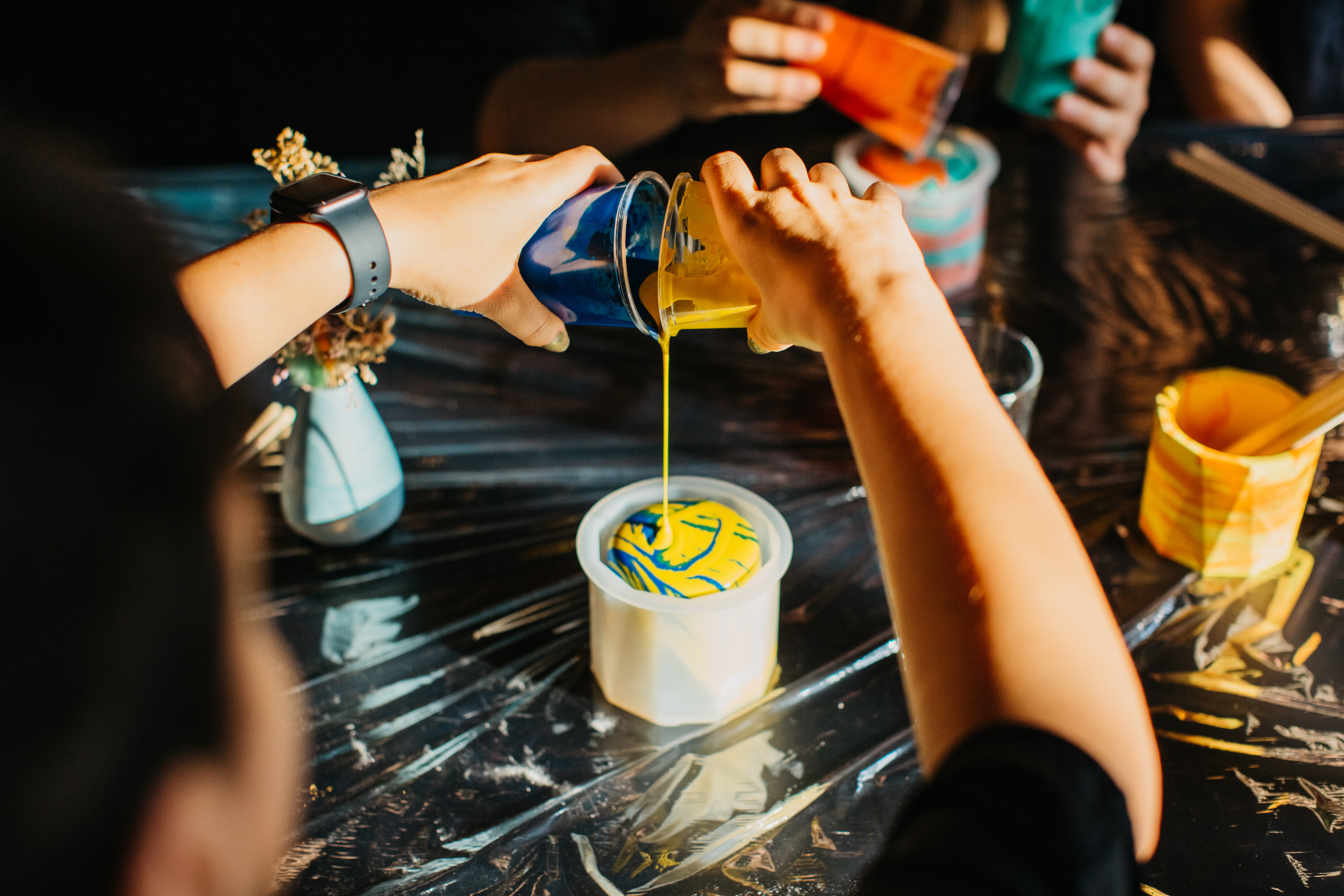 Two hands pouring paint into a round mould
